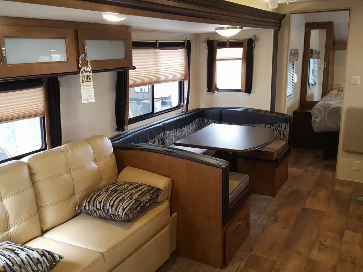 Spacious RV rental interior featuring a sofa, L-shaped dinette, and a cozy bedroom area.. Forest River Wildwood 27DBK 2017