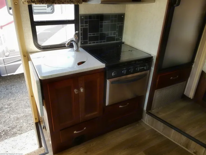 RV rental interior: cozy kitchen with white countertop, sink, gas stove, oven, and wood cabinets.. Forest River Forester 2018