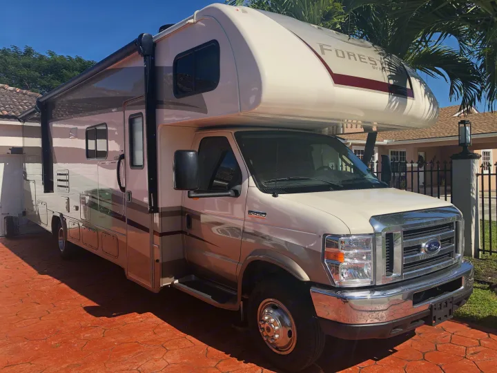 Spacious beige and gray Class C Forester RV rental, parked on a sunny driveway, ready for adventure.. Forest River Forester 2020