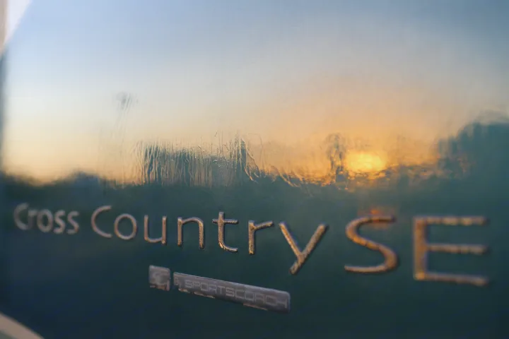 Detail shot of an RV: "Cross Country SE By SPORTSCOACH" badge. Golden sunset reflects on the surface. Find your next rv rental.. Coachmen Cross Country 2005