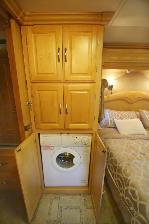 RV rental bedroom with integrated laundry: compact washing machine and storage cabinets.. Coachmen Cross Country 2005