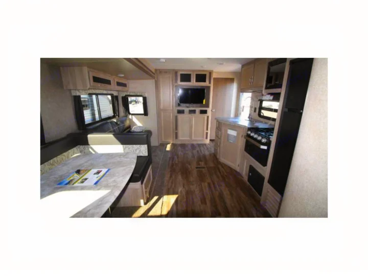 An RV rental interior featuring a kitchen with stove, sink, and fridge, plus a dinette and entertainment center.. Coachmen Catalina 2019