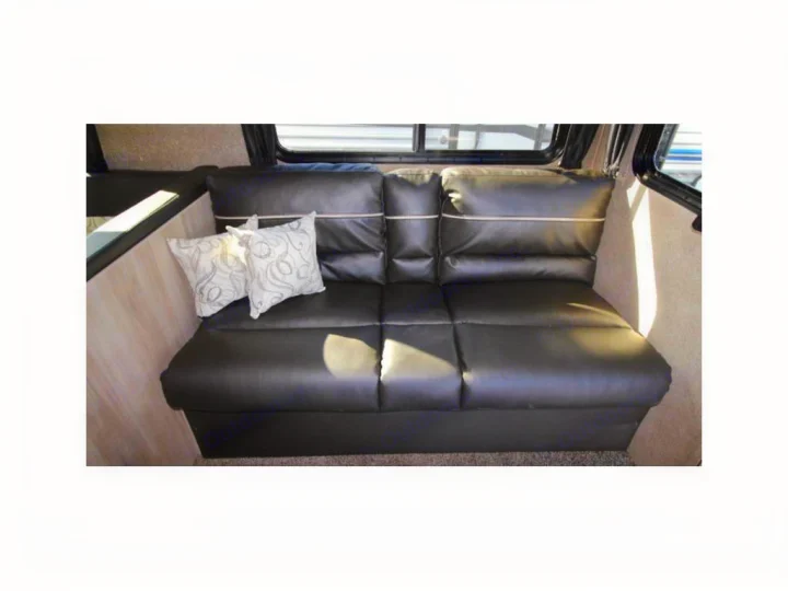 Black sofa and decorative pillows inside an RV rental, offering comfortable seating for your travels.. Coachmen Catalina 2019