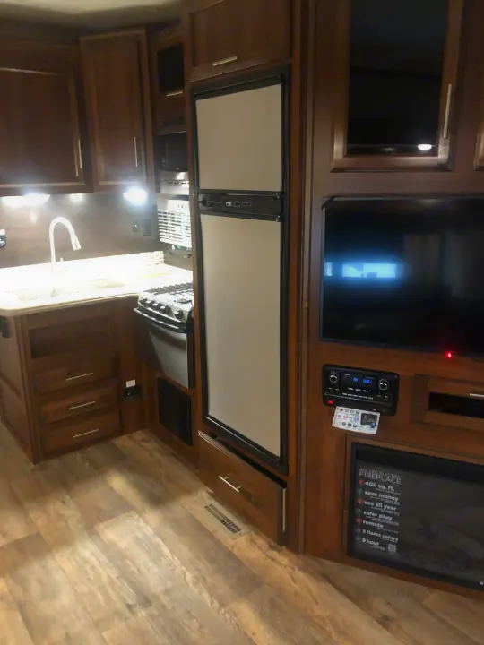 This modern RV rental features a compact kitchen with sink and stovetop, a refrigerator, entertainment center with TV, and an electric fireplace.. Jayco Eagle Super Lite 2018