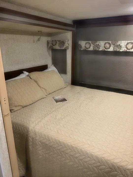 Relax in this RV rental's cozy bedroom, featuring a quilted bed, reading light, and blackout blinds.. Forest River Forester 2020