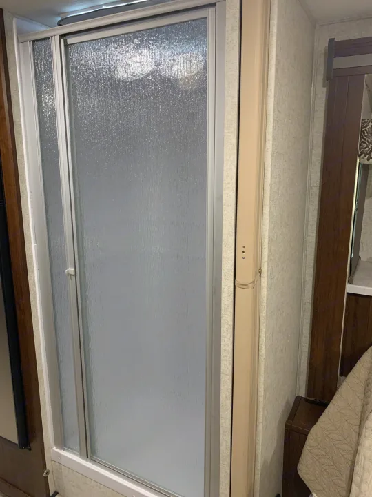 Inside an RV rental: A detailed view of a shower enclosure with privacy-providing frosted glass doors and textured walls.. Forest River Forester 2020
