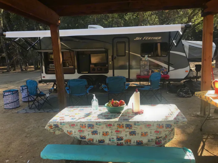 RV rental campsite features a Jay Feather travel trailer with outdoor kitchen, picnic table & chairs under the awning.. Jayco Jay Feather 2016