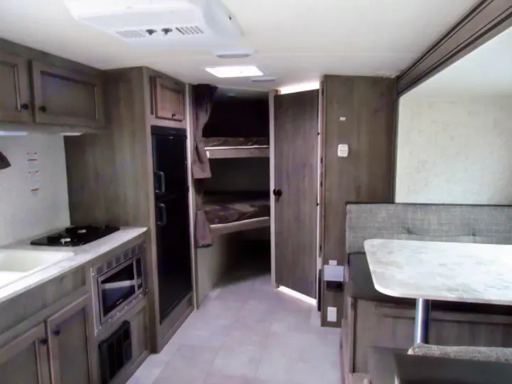 RV rental interior: Kitchen with stove, microwave, fridge, dinette, and bunk beds.. Coachmen Apex 208BHS 2023