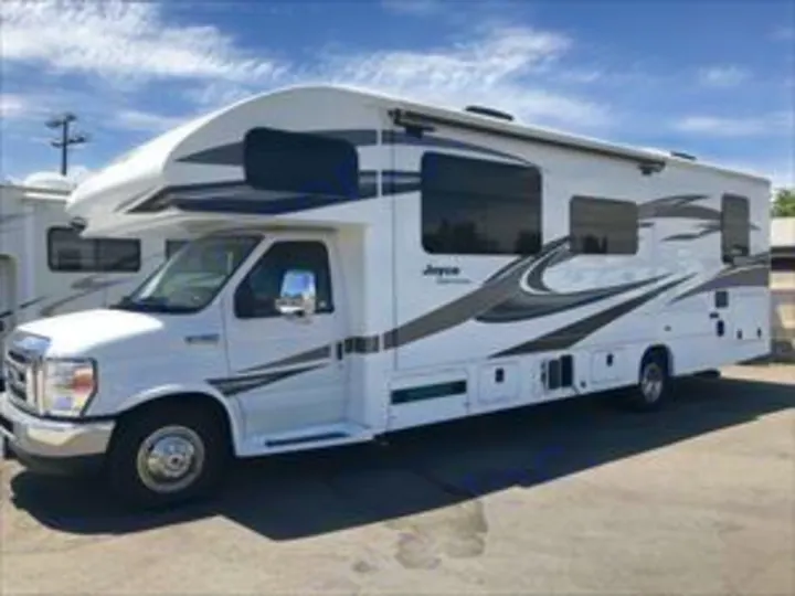 A clean white Jayco Class C RV rental with gray graphics, ready for travel. This motorhome offers comfortable adventures.. Jayco Greyhawk 2019