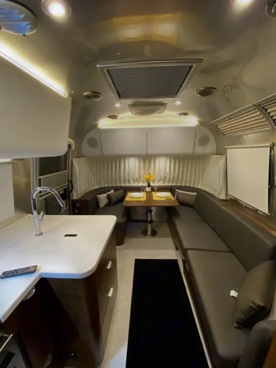 Explore this spacious Airstream **rv rental** interior: sleek kitchen, U-shaped lounge/dinette, and ambient lighting.. Airstream Globetrotter 2020