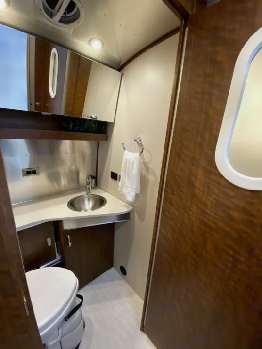 Compact bathroom interior of an RV rental, featuring a sink, toilet, and mirror, designed for efficient use of space.. Airstream Globetrotter 2020