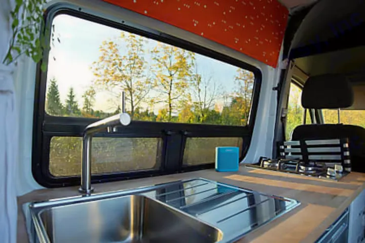 RV rental camper van interior: compact kitchen with sink, stove, and a scenic view from the window.. Mercedes-Benz Sprinter 2017