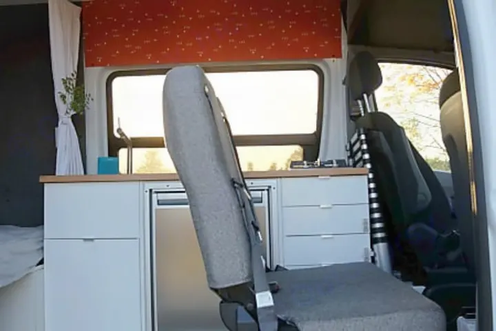 Inside a camper van rv rental: grey seat, compact kitchen with sink, fridge, & window. Ready for adventure.. Mercedes-Benz Sprinter 2017