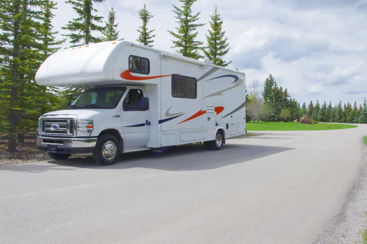 This white rv rental is parked on a winding road among evergreen trees, ready for adventure.. Forest River Sunseeker 2015