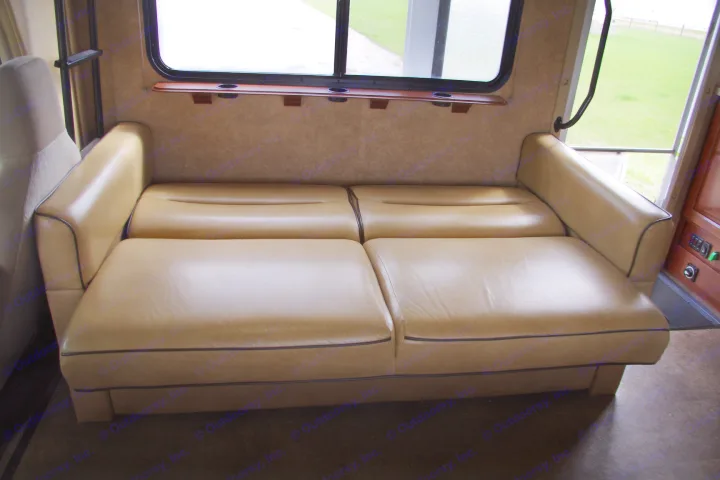 RV rental interior features a comfortable, beige convertible sofa with black piping, located by a window, ideal for relaxing or sleeping.. Forest River Sunseeker 2015