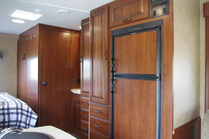 Explore this RV rental's interior: wood cabinetry, Dometic fridge, and a glimpse of the bedroom. Practical and comfortable.. Forest River Sunseeker 2015