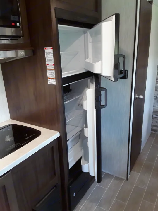 RV rental kitchen with two open top-loading fridges & microwave, perfect for travel.. Forest River Wolf Pup 2020