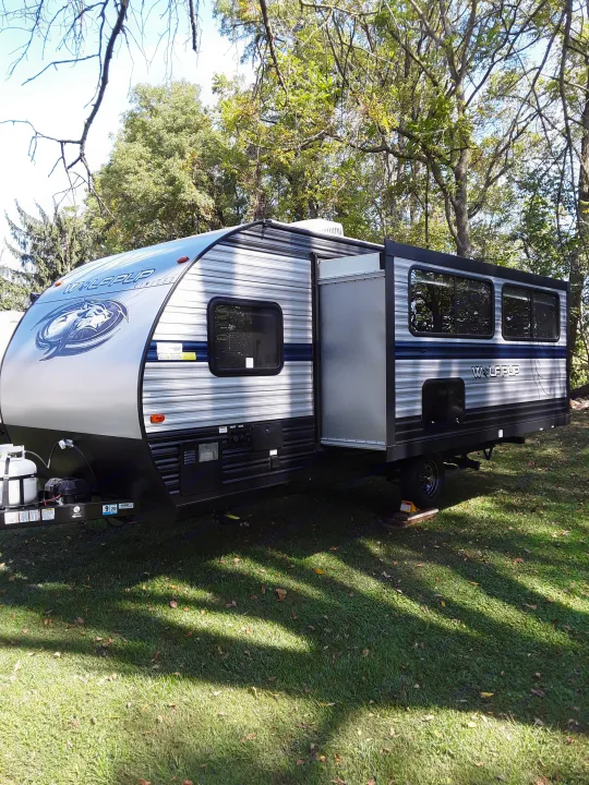 Modern Wolf Pup travel trailer (RV rental) under trees on green grass, ready for adventure.. Forest River Wolf Pup 2020