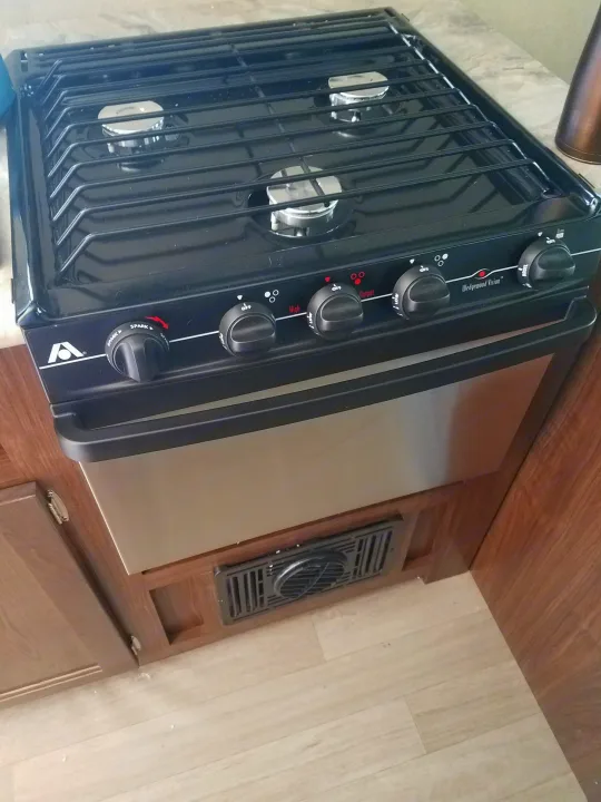 This Wedgewood Vision RV rental kitchen features a compact black 3-burner stovetop, oven, and controls for easy cooking on the go.. Coleman Coleman 202RD 2017