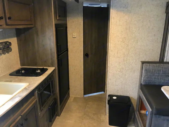 RV rental interior showcasing a compact kitchen (sink, stove, microwave, fridge) and a cozy dinette. Functional travel space.. Coachmen Apex Nano 2019