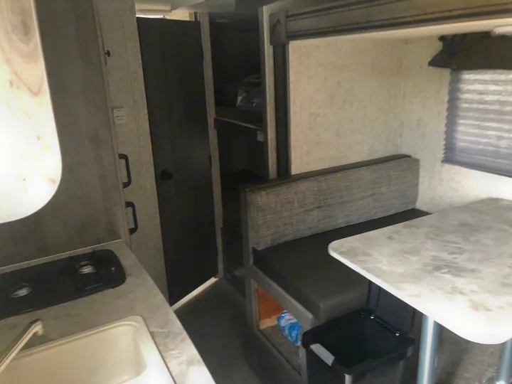 Inside this RV rental: view of a dinette table, kitchen with sink & stove, plus storage. Perfect for travel & camping.. Coachmen Apex Nano 2019