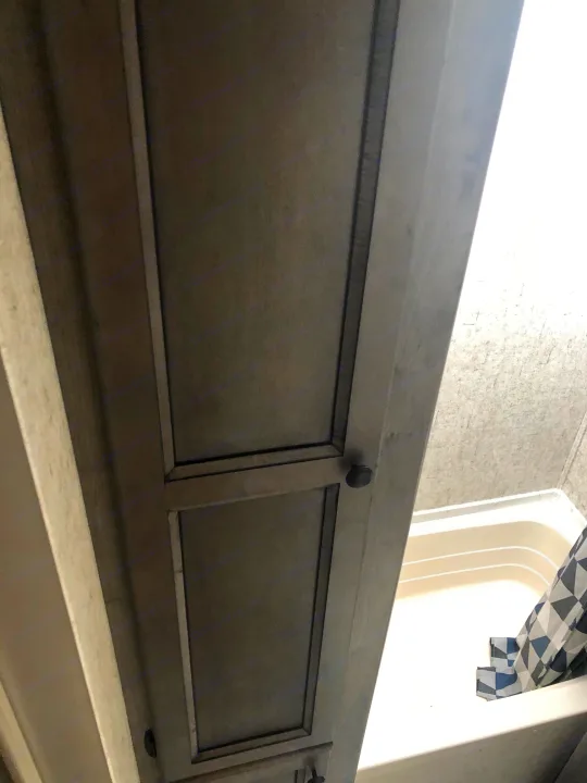 RV rental interior: close-up of sleek cabinets. Beyond, a shower with a patterned curtain in a modern recreational vehicle.. Coachmen Apex Nano 2019