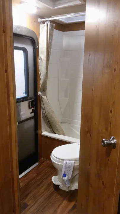 Inside an RV rental: a compact bathroom with toilet, shower, and wood-look flooring.. Gulfstream Cabin Cruiser 2018