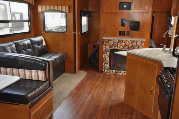 Inside this cozy RV rental: sofa, dining booth, kitchen, and stone fireplace.. Gulfstream Cabin Cruiser 2018