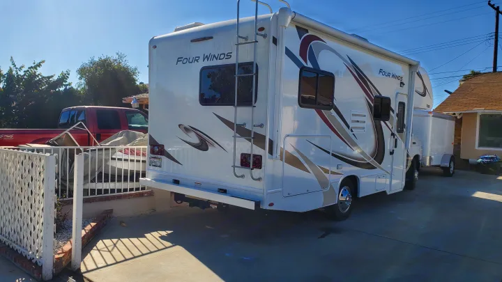 A white Four Winds Class C motorhome, ready for an RV rental adventure, parked in a driveway on a sunny day.. Thor Motor Coach Four Winds 2019