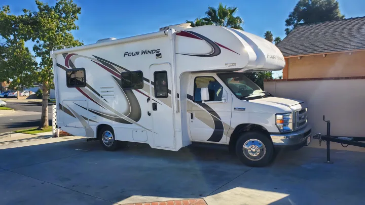 This white Four Winds Class C RV, ideal for your next rv rental adventure, is parked on a sunny driveway.. Thor Motor Coach Four Winds 2019