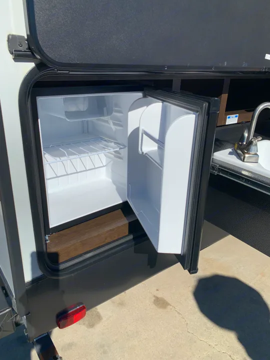 Outdoor kitchen for your RV rental: features an open mini-fridge with empty shelves & a sink. Perfect for camping!. Cruiser Rv Corp Shadow Cruiser 2019