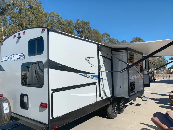 A sleek grey and white Shadow Cruiser travel trailer with its awning extended, ideal for an RV rental. Ready for adventure!. Cruiser Rv Corp Shadow Cruiser 2019