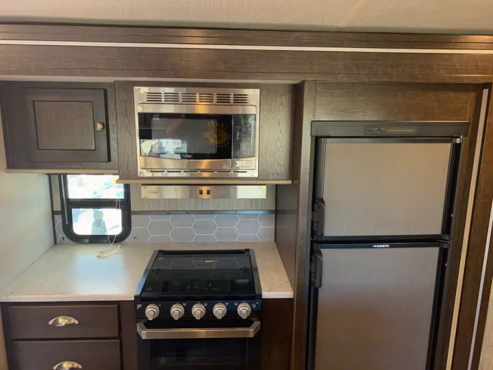 Modern RV rental kitchen with microwave, stove, oven, Dometic refrigerator, and storage cabinets.. Cruiser Rv Corp Shadow Cruiser 2019