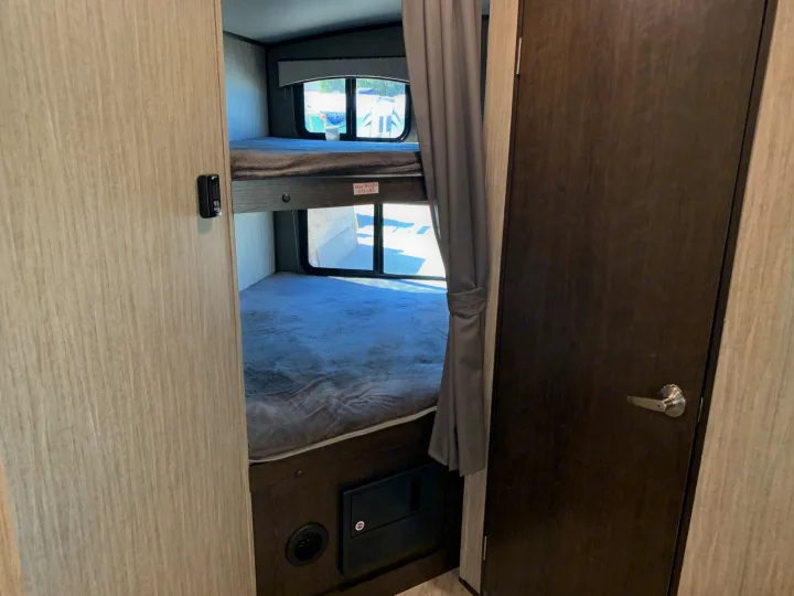 RV rental interior features cozy bunk beds with windows and a privacy curtain, ideal for family trips.. Cruiser Rv Corp Shadow Cruiser 2019