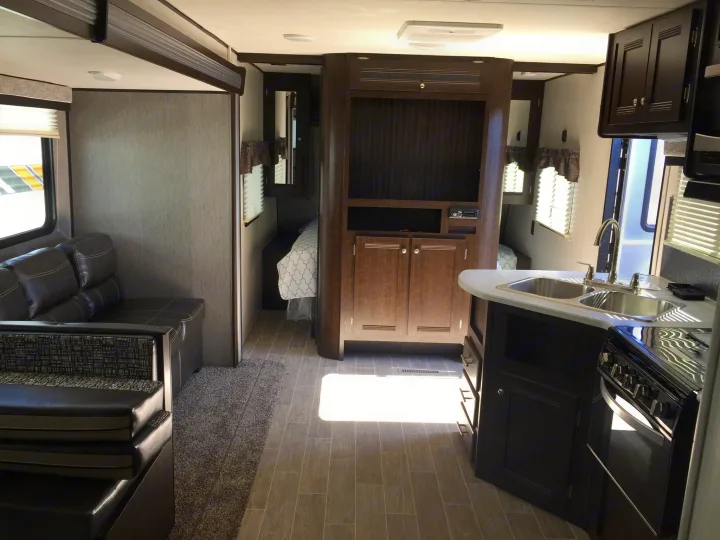 Modern rv rental interior with living area, kitchen, and private bedrooms. Perfect for spacious travel adventures.. Heartland Trail Runner 2020