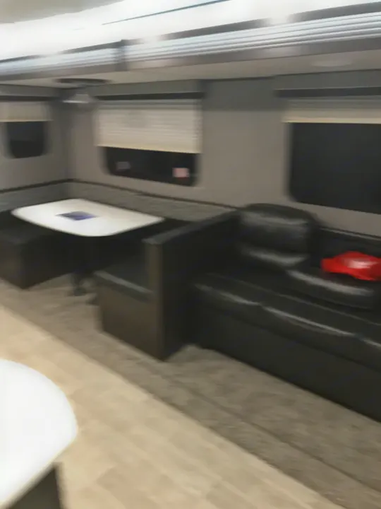 Inside this RV rental: a compact dinette with bench seating, a black sofa, and windows. Ready for travel.. Heartland Trail Runner 2020