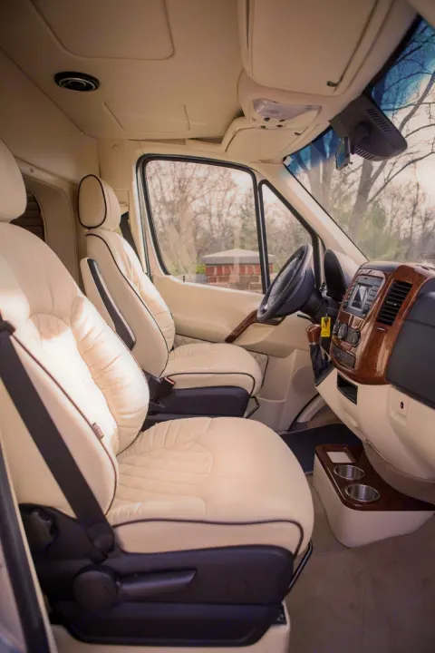 Luxury RV rental interior: cream quilted seats, wood-trimmed dashboard, and ample space for a comfortable journey.. Other Other 2020