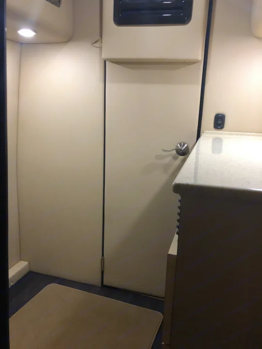 Cozy rv rental interior with a door leading to a bathroom, light-colored walls, a counter, and a floor rug.. Other Other 2020