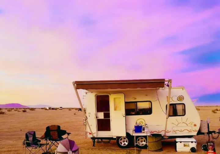 This RV rental is perfectly set for boondocking in the desert. A white travel trailer under a breathtaking pink and purple sunset sky.. Dutchman Eco 2010