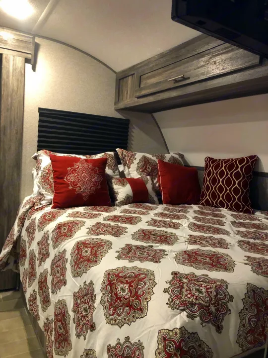 Explore a well-appointed RV rental bedroom with a comfy bed, decorative linens, and convenient overhead storage.. Forest River Salem 2020