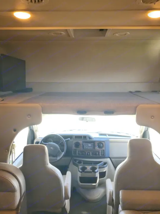 Spacious RV rental interior featuring the cockpit, dashboard, driver's seat, and overhead bunk for comfortable travel.. Thor Motor Coach Four Winds 2017