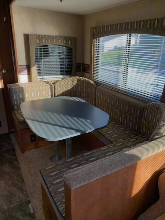 RV rental dinette interior with table, benches, and bright windows. Cozy and functional space inside a camper.. Shasta Revere 2012