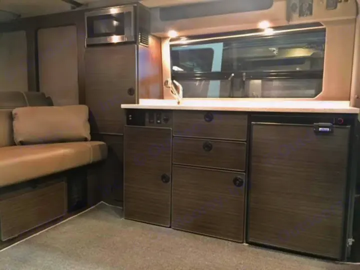 Explore our RV rental's versatile interior: a well-equipped camper kitchen with microwave, fridge, & comfy seating area.. Mercedes Sprinter 2018