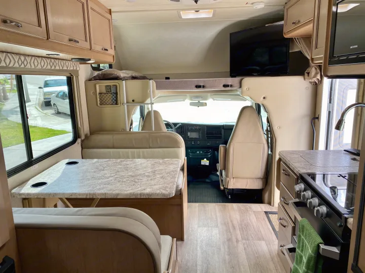 Spacious RV rental interior: dinette with table, functional kitchen, and cozy cab-over bunk. Bright, inviting space.. Thor Motor Coach Four Winds 2020