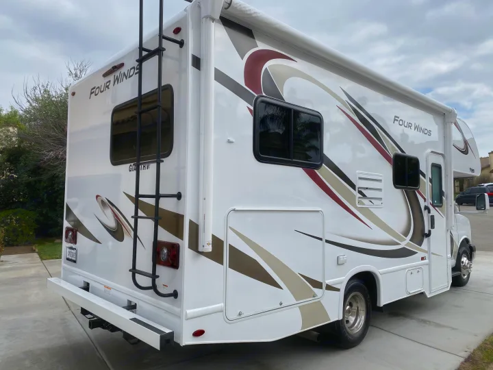 White Four Winds Class C RV with graphic decals and a rear ladder, perfect for an rv rental or motorhome trip.. Thor Motor Coach Four Winds 2020