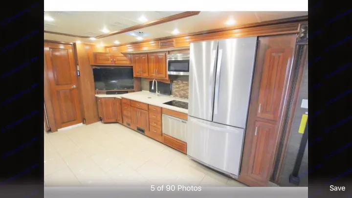 RV rental: Modern kitchen featuring a large stainless steel fridge, microwave, sink, and wood cabinetry on tiled floors.. Holiday Rambler Endeavor 2018