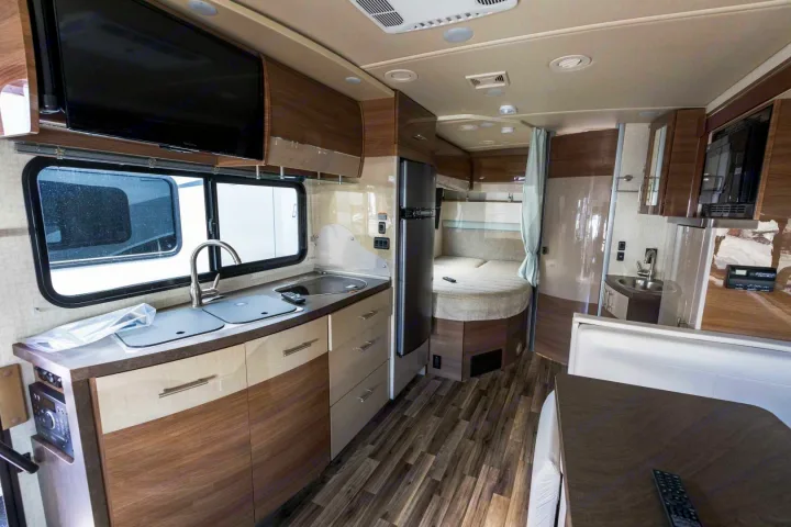 Inside an RV rental: features a compact kitchen, bed, dining space, and bathroom vanity for comfortable travel.. Winnebago View 2017