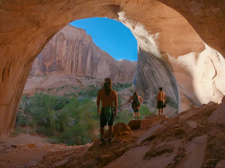 Three hikers enjoy incredible canyon views from a vast rock arch, an ideal RV rental road trip destination.. Winnebago View 2017