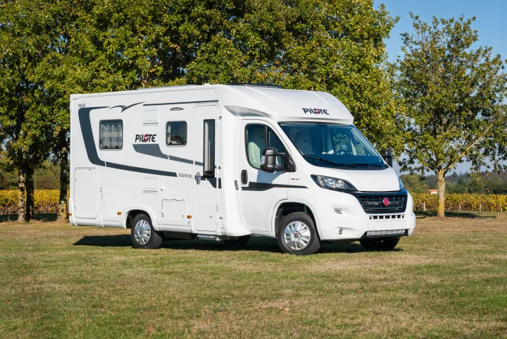 Clean white RV rental parked in a scenic, sunny field next to trees and a vineyard.. Pilote P650 C 2025