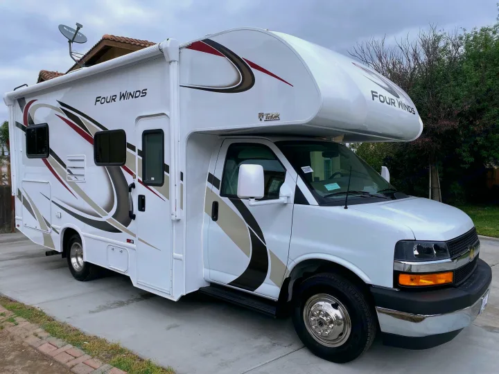 A modern white Class C RV rental, a Thor Four Winds motorhome, parked on a clean driveway, perfect for your next road trip.. Thor Motor Coach Four Winds 2020